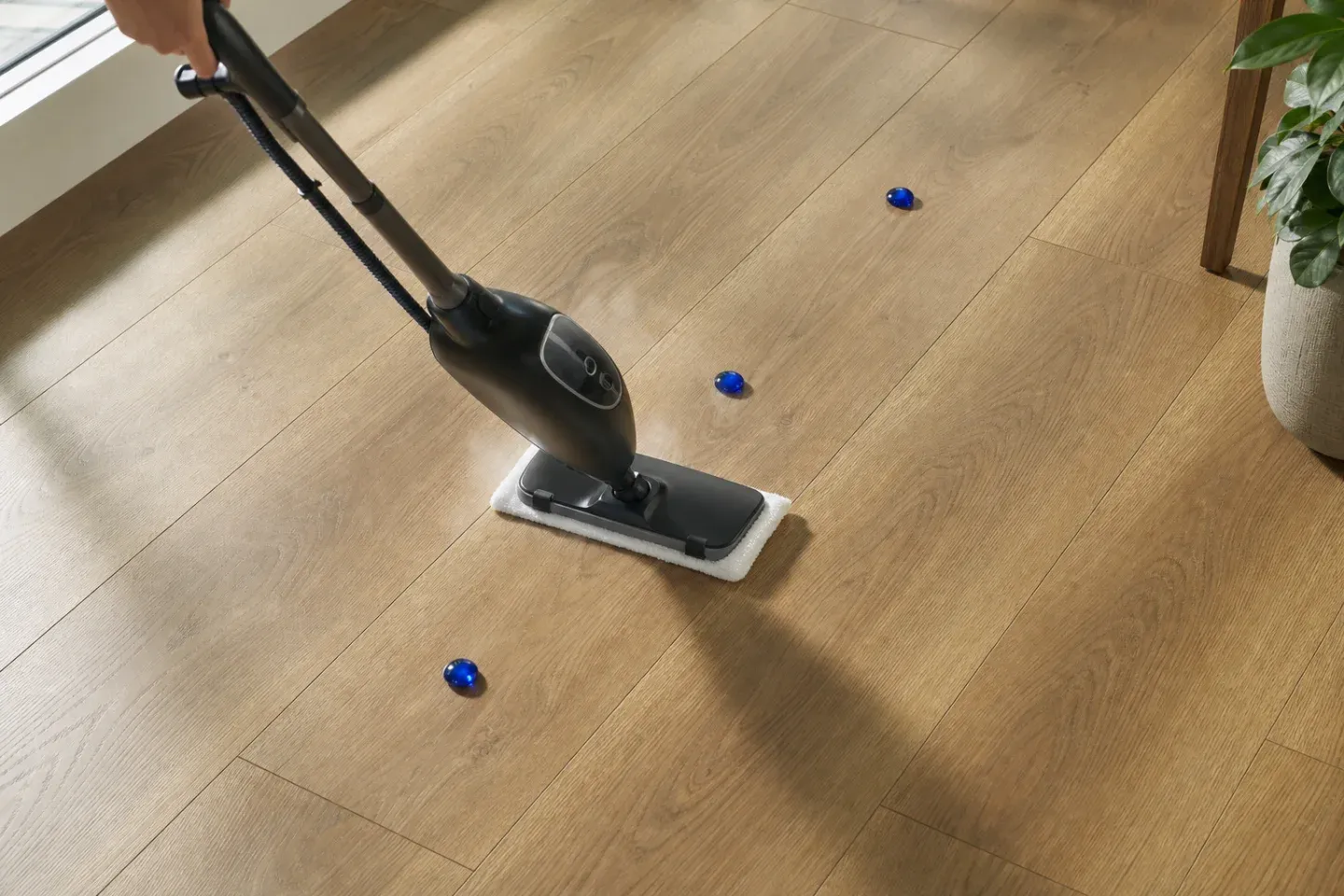 An unbranded steam mop moving continuously over approved LVP with a faint controlled vapor trail