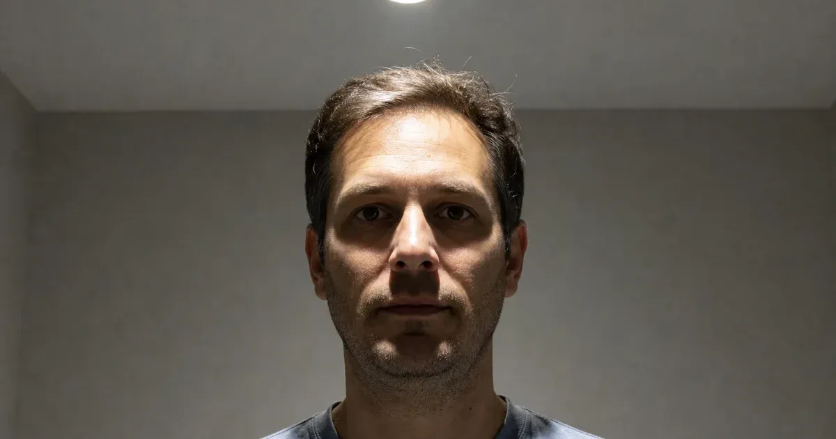 A person beneath a single recessed ceiling light with deep shadows in the eye sockets and beneath the nose and chin